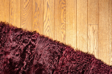 A fragment of the coating (carpet) of natural Burgundy fur on the parquet floor, interior decoration