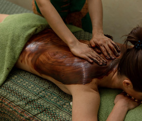 Back massage with chocolate moisturizing mask. Masseur work process. Masseur. A Thai massage...