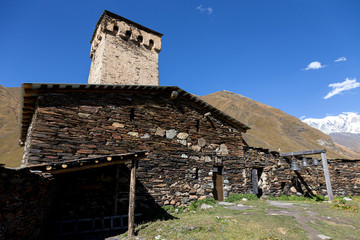 Fototapeta na wymiar Old stone houses and fences of the village of Ushguli in a beautiful autumn landscape with white clouds in Svaneti. Georgia