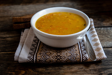 Pea soup in a white ceramic bowl on a kitchen napkin against the background of old wooden boards. Cooking homemade food.