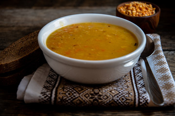 Pea soup in a white ceramic bowl on a kitchen napkin against the background of old wooden boards. Cooking homemade food.