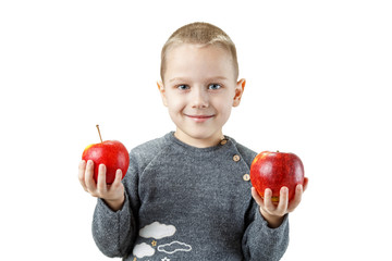 A little European boy holds two red apples in his hand. Joy and admiration. Studio photography on an isolated white background.