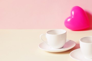 Fototapeta na wymiar Two small cups of coffee and a pink heart. Photo for Valentine's Day