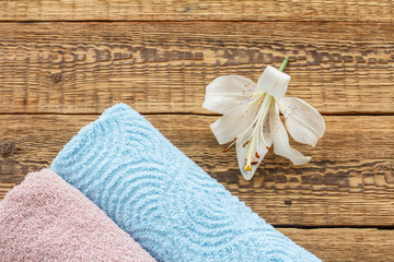 Soft terry towels with lily flower on wooden background.