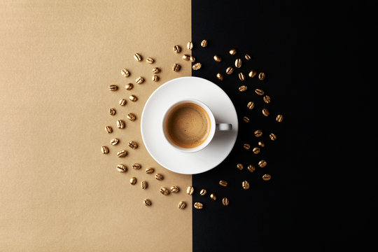 Cup of coffee and coffee beans on gold black background. Creative flat lay. Top view.