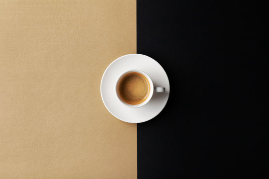Cup of coffee on gold black background. Minimalistic flat lay. Top view.