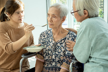 Asian woman feeding tired senior patient,anorexia,eat less food,depressed female elderly suffer...