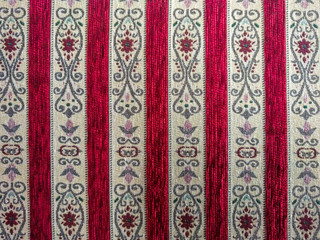 Oriental looking fabric with interesting repeating pattern in dark red color with eastern shapes used for interior textile decoration