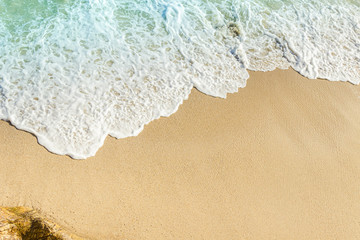 Fototapeta na wymiar sand beach and white foam blue wave from the sea