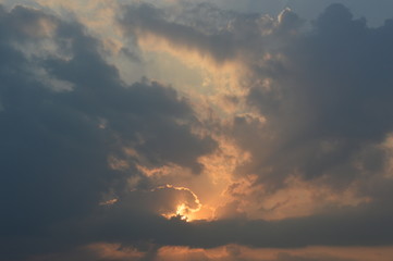 The rising sun in the morning surrounded by clouds.