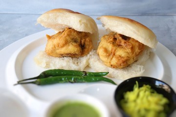 Vada pav or wada pao is a vegetarian fast food dish native to the state of Maharashtra. Famous Mumbai street food served with green chutney and fried green chili. Copy space