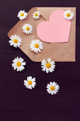 open paper envelope with a heart symbol and real daisies. flower love valentine