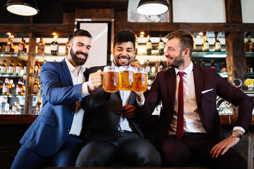 Team of colleagues socializing at the bar and drinking beers