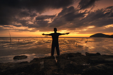 Fototapeta premium silhouette of back of a man operating his phone against beautiful sunset at beach