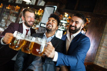 Young businessmen are drinking beer, talking and smiling while resting at the pub