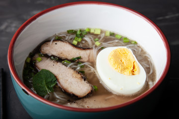 Composition with a bowl of rice noodles, meat and vegetables