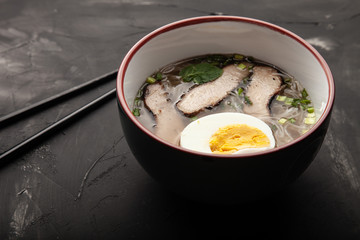 Composition with a bowl of rice noodles, meat and vegetables