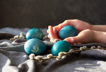 Naturally dyed blue Easter eggs and willow branches. Girl holding Easter egg in her hands