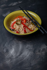 Composition with a bowl of rice noodles, meat and vegetables