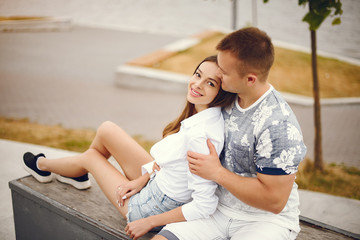 Cute couple sitting in a city. Girl in a white shirt.