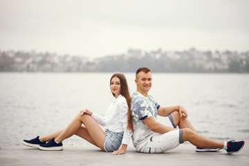 Cute couple sitting near water. Girl in a white shirt. Pair by the river