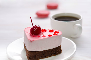 souffle cake in the form of heart  with cup of coffe and macaroons on a wooden table