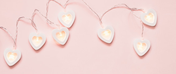 Romantic pink pastel background with heart garland. Valentine's day decoration, banner format