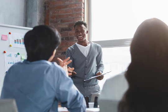 Cheerful Black Employee Talking To Colleagues While Presentation