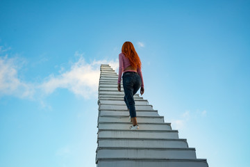 The girl goes up the stairs that goes into the sky.