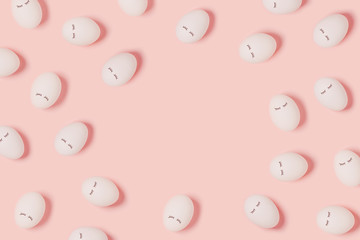 Happy Easter. Pattern with white eggs with painted eyes on pink background. Flat lay, top view, copy space.