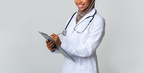 Black Muslim Medical Intern Girl In Hijab Writing Notes To Clipboard