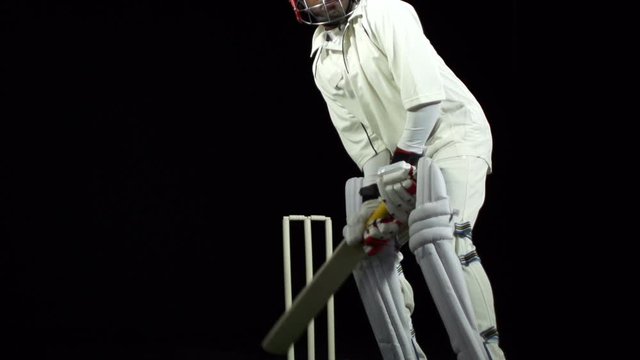 Cricket Batsman bowled out - Wicket. The ball hits the stumps. Black background. Dressed in white.