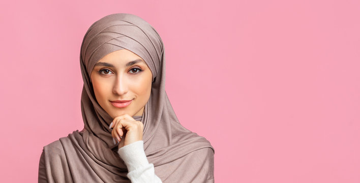 Portrait of confident islamic woman in headscarf posing over pink background