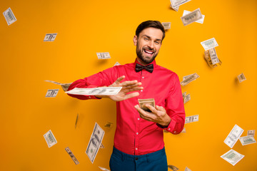 Photo of crazy funny guy hold fan of money bucks waste jackpot throw away banknotes money falling wear trendy red shirt bow tie clothes isolated yellow color background - obrazy, fototapety, plakaty