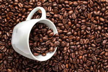 White cup with coffee beans on a background of coffee beans