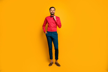 Fototapeta na wymiar Full body photo of funny macho man good mood friendly smiling fixing hipster necktie wear stylish red shirt with bow tie blue trousers shoes isolated yellow color background