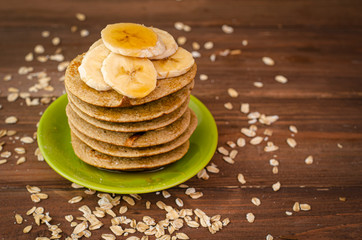 Breakfast oatmeal pancakes with banana and honey for a breakfast on wooden background closeup,  selective focus