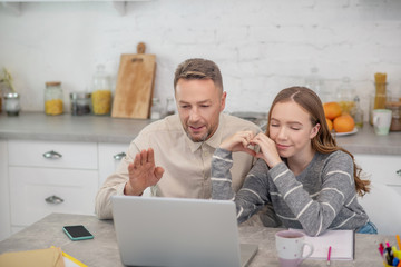 Obraz premium Long-haired girl in grey shirt and her father having a video call