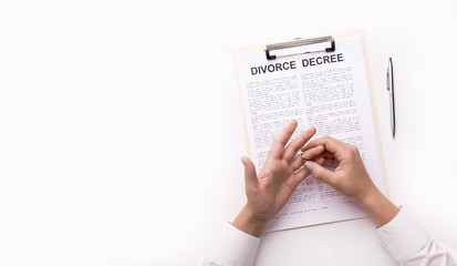 Wife taking off wedding ring and signing up divorce decree