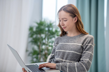 Naklejka premium Long-haired girl in grey shirt holding a laptop