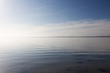 Minimalist glassy calm coastline seascape and horizon on bright morning in South Australia.