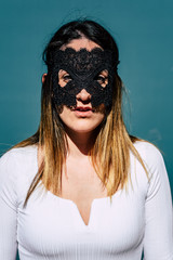 Vertical portrait of attractive young woman with black mask on her face and white shirt, serious gesture, to keep her privacy.