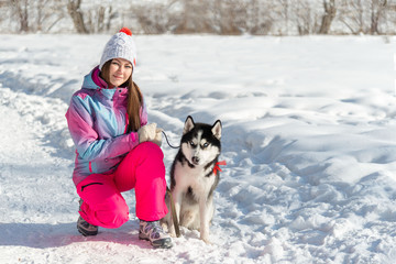 a young woman walks in the winter forest with her pet. friend of the dog with blue eyes, husky, Siberian.