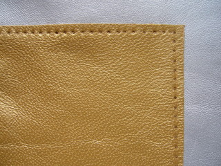 The texture of the skin close-up. Genuine haberdashery leather in gold color. Genuine Leather