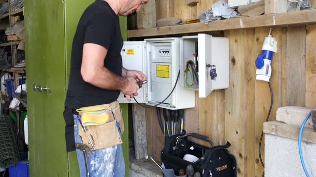 Electrician working at Fuse box and is doing some wiring. Crane Shot of the Technician