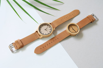 Top view of 2 brown wooden watches with palm leaf