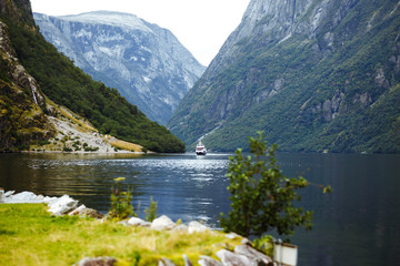 A ship sailing in Norwegian fjords. Amazing nature view with fjord and mountains. Beautiful reflection. Travelling, lifestyle, adventure, wild nature concept.