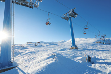 Ski lift with seats going over the mountain and paths from skies and snowboards. Beautiful winter landscape.