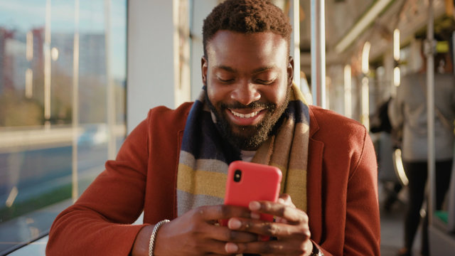 Face smiling young african american man use smartphone sitting in tram traffic typing at sunny day handsome passangers stylish transportation using way internet online texting portrait guy slow motion
