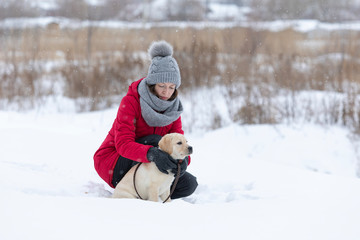 Beautiful young woman hugging her dog in snow